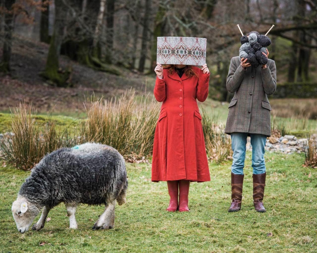 Rachel and Alice of Cable & Blake pose with their products next to a grazing Herdwick sheep