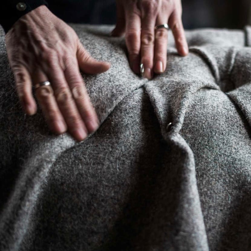 Hands apply the finishing touches to a Herdwick fleece decorated upholstery