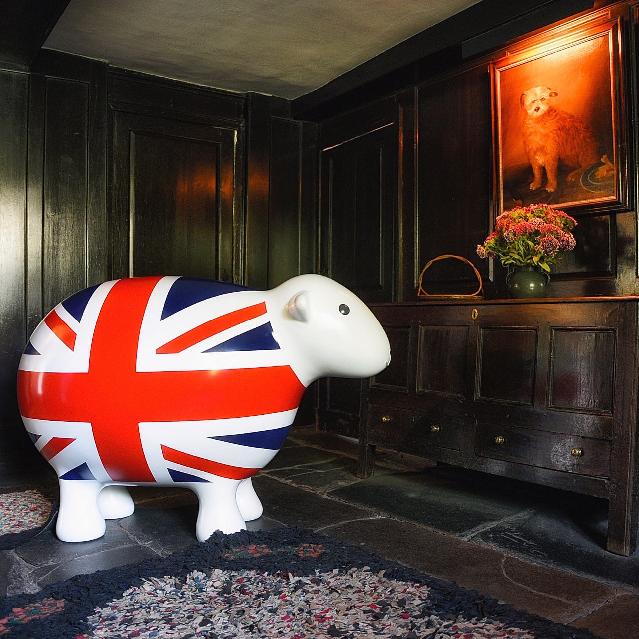 Giant GB Herdy inside Dove Cottage and its wooden clad walls and antique furniture, looking at a portrait painting of a dog