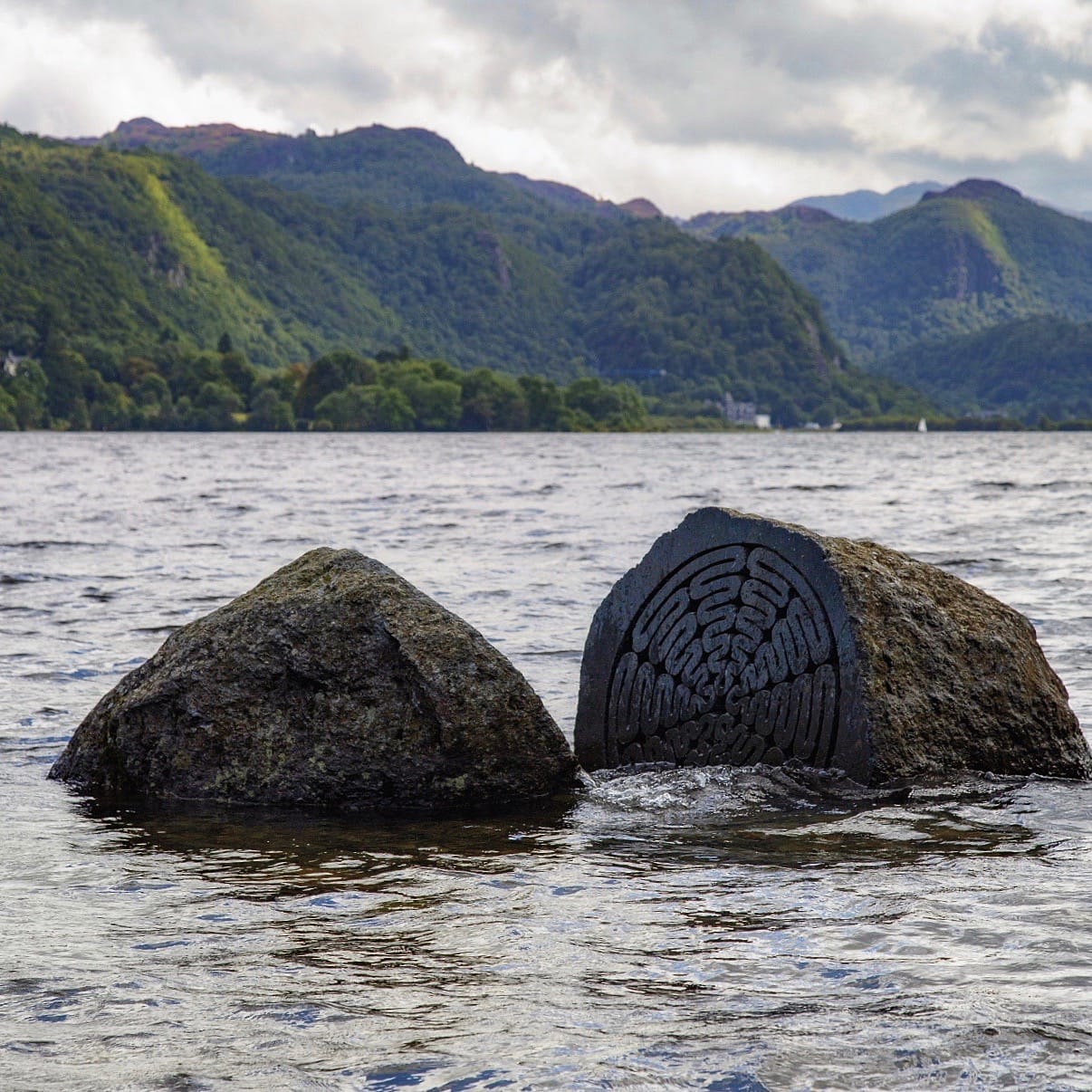 The Hundred Year Stone, half submerged in the waters of Derwentwater, with the Borrowdale fells in the distance.