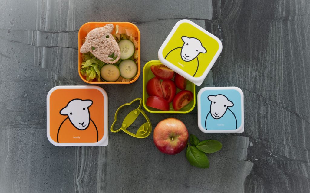 Herdy Snack Boxes, filled with sandwiches and fruit on a slate counter top